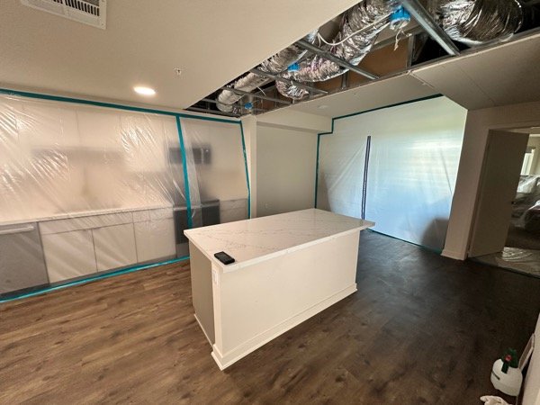 Existing quartz island in kitchen with exposed ceiling ductwork visible above
