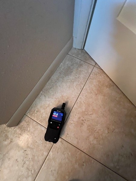 Thermal moisture meter checking a ceiling vent area inside a plastic-contained room
