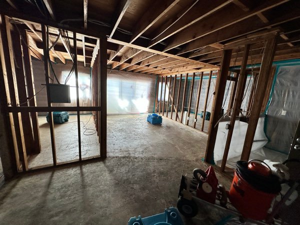 Exposed wall framing with drying equipment running during a structural drying project